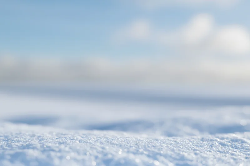 Snow-covered ground with soft bokeh blur under winter daylight sky