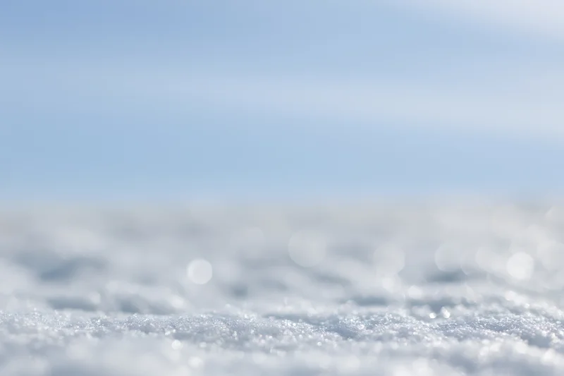 Soft out-of-focus snow surface under winter daylight with bokeh effect