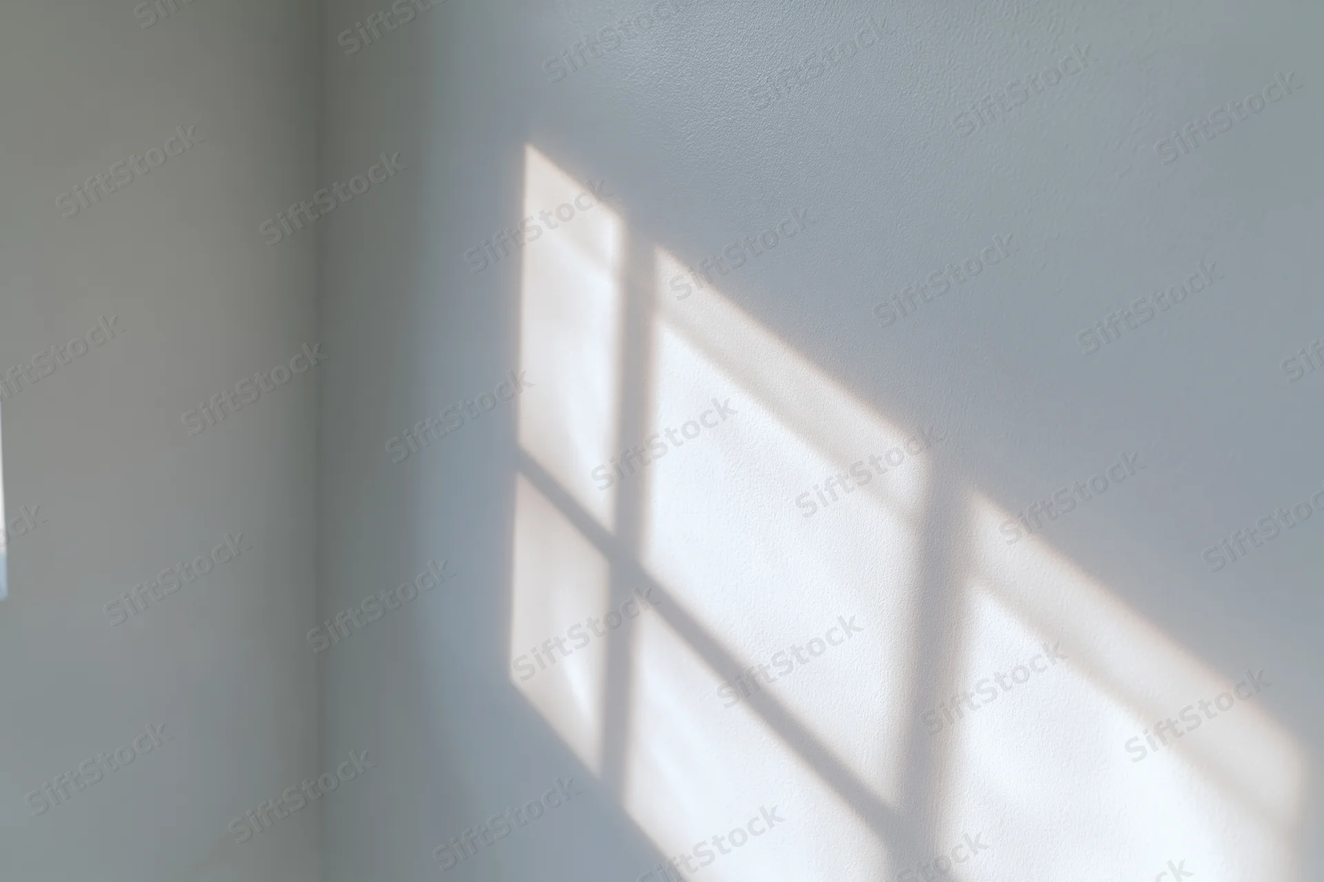 Soft grid shadow from a window cast across a plain white interior wall