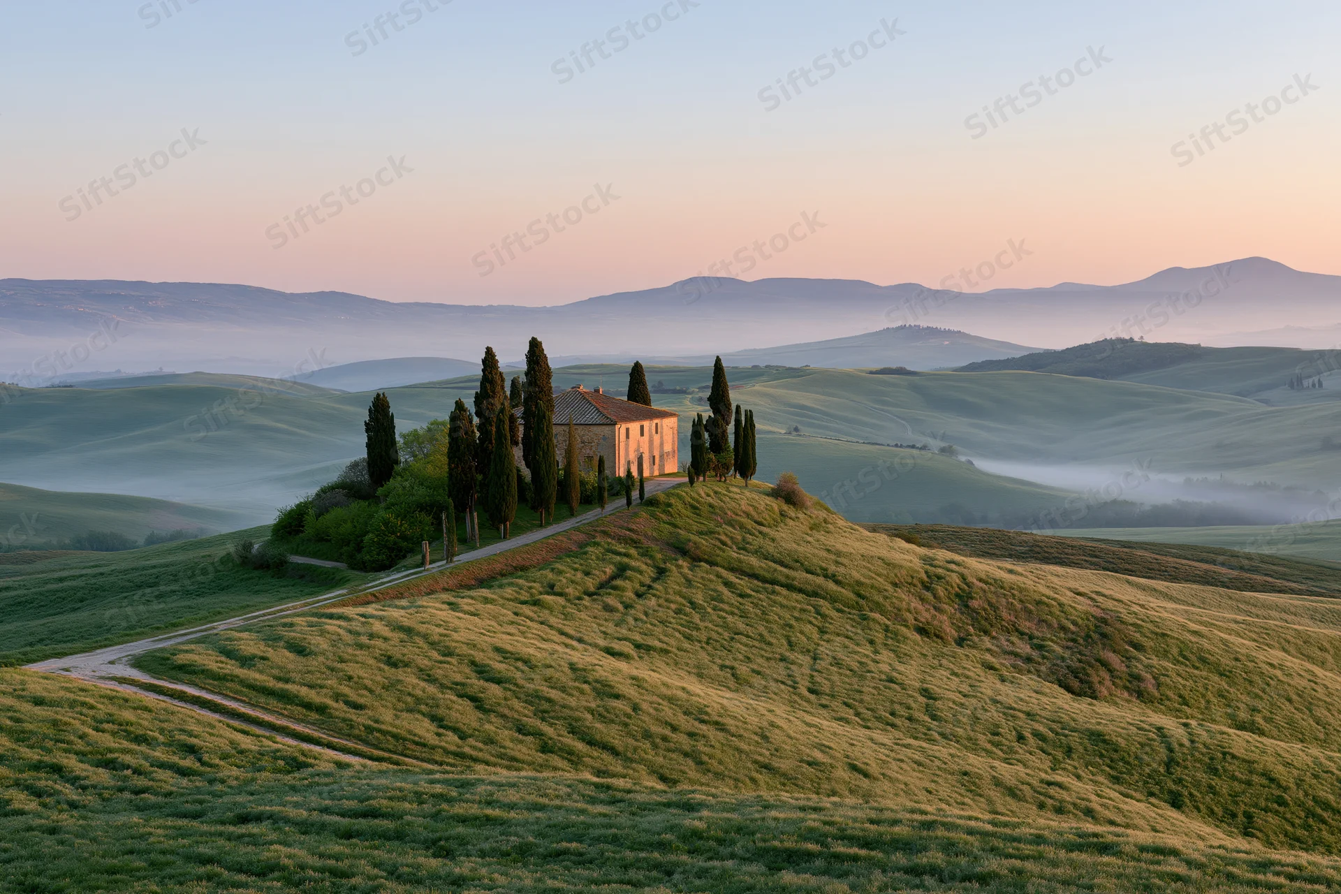 Stone farmhouse surrounded by tall cypress trees on a grassy hill at sunrise in tuscany
