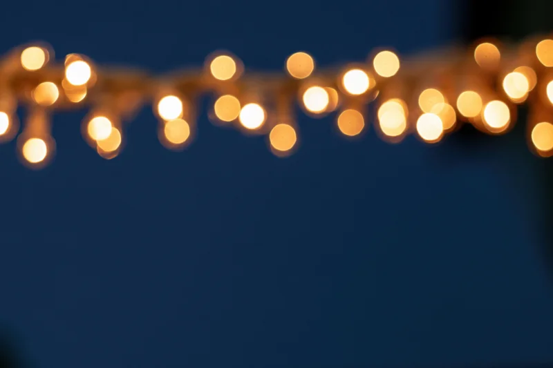 String lights glowing softly out of focus at the top of the frame against a dark blue background with copyspace below