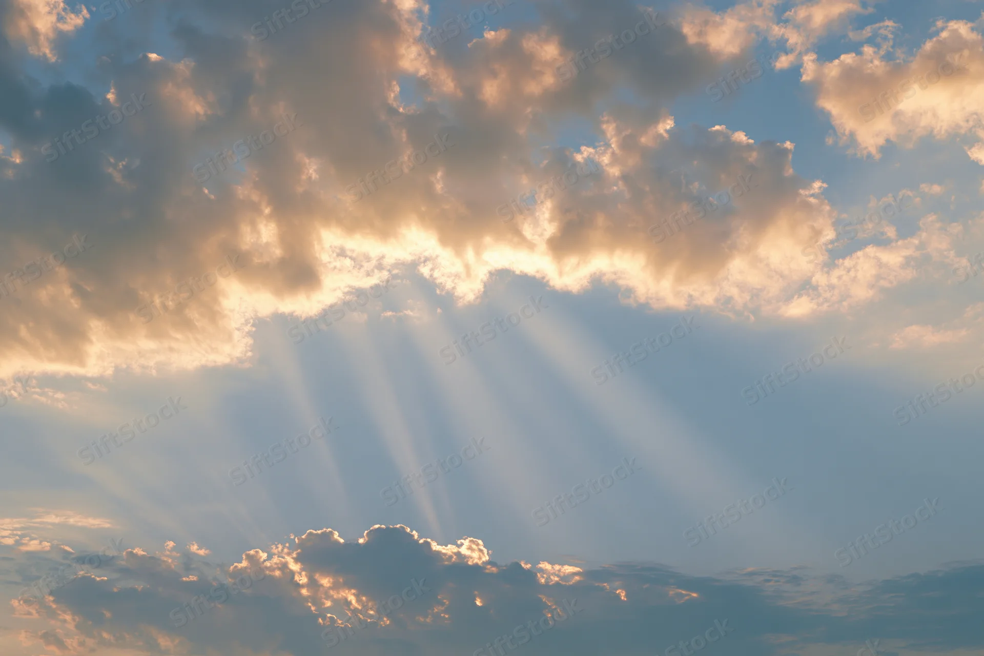 Sunlight breaking through layered cumulus clouds in the sky