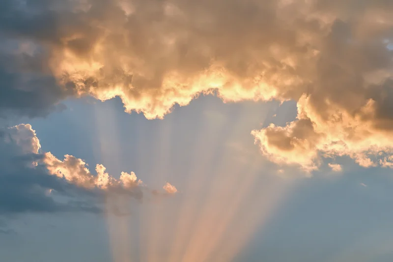 Sunlight breaking through layered cumulus clouds in the sky