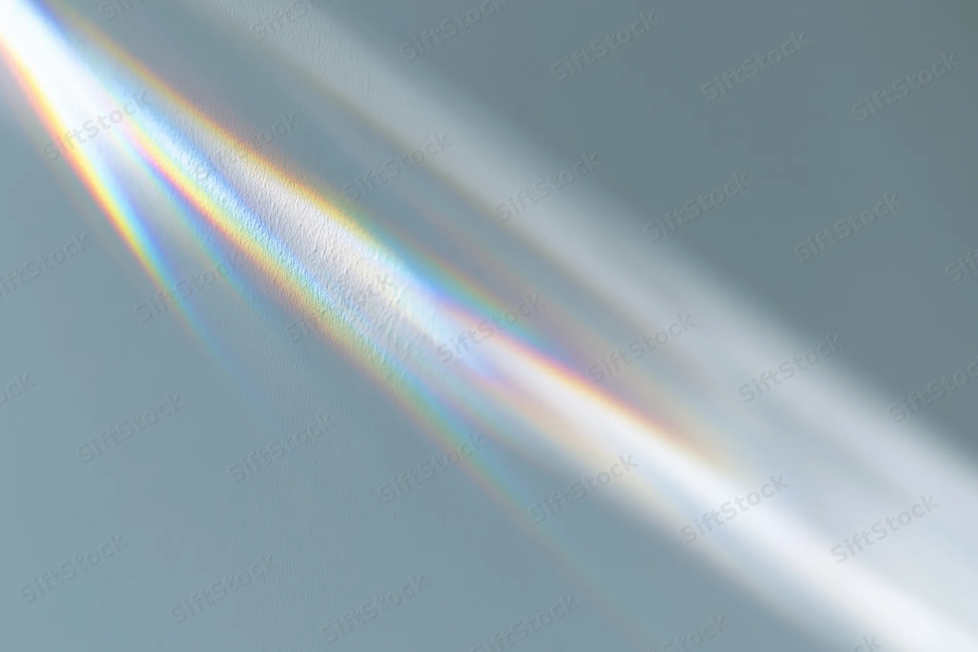 Sunlight refracting through a glass prism casting a rainbow spectrum on a wall