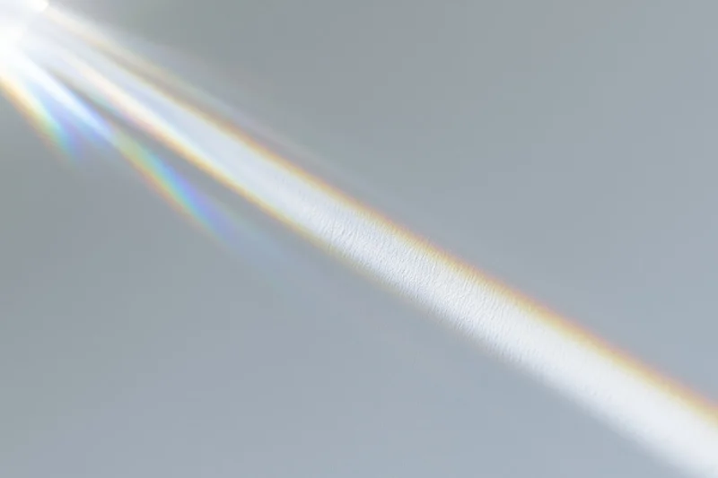 Sunlight refracting through a glass prism casting a rainbow spectrum on a light surface