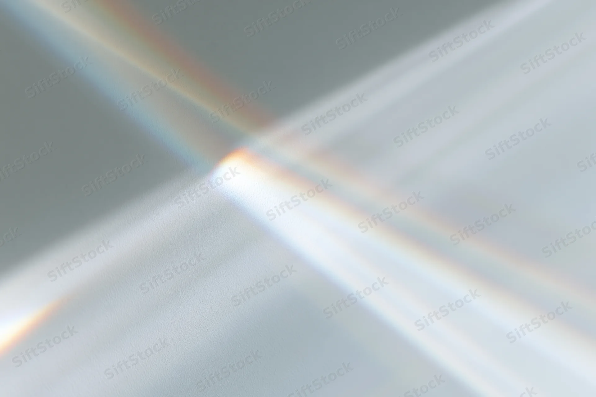 Sunlight refracting through a glass prism casting a rainbow spectrum on a neutral surface