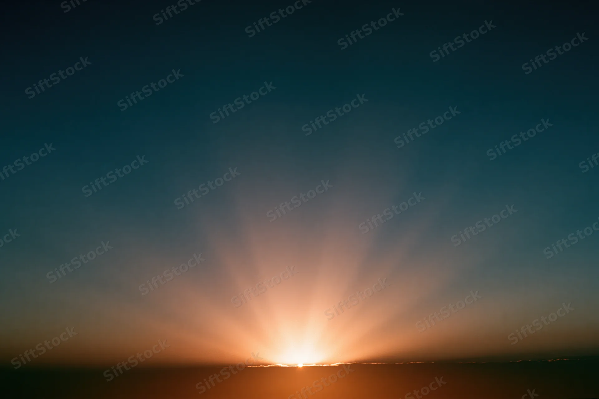 Sunrise light burst radiating upward from the horizon in a wide sky view