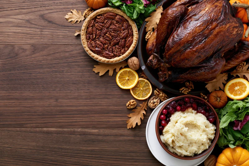 Thanksgiving dinner spread arranged along the right side of a wooden table with copyspace on the left