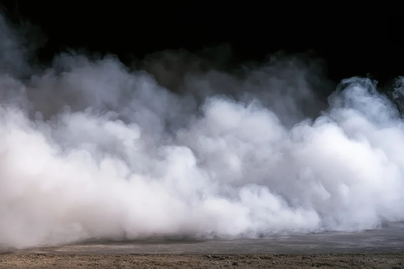 Thick white smoke billowing upward from a dark concrete floor