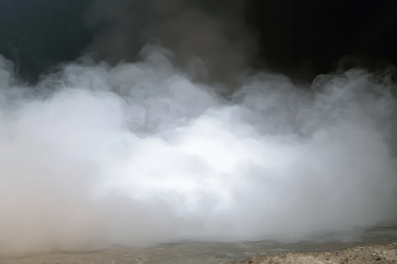 Thick white smoke billowing upward from a dark concrete floor