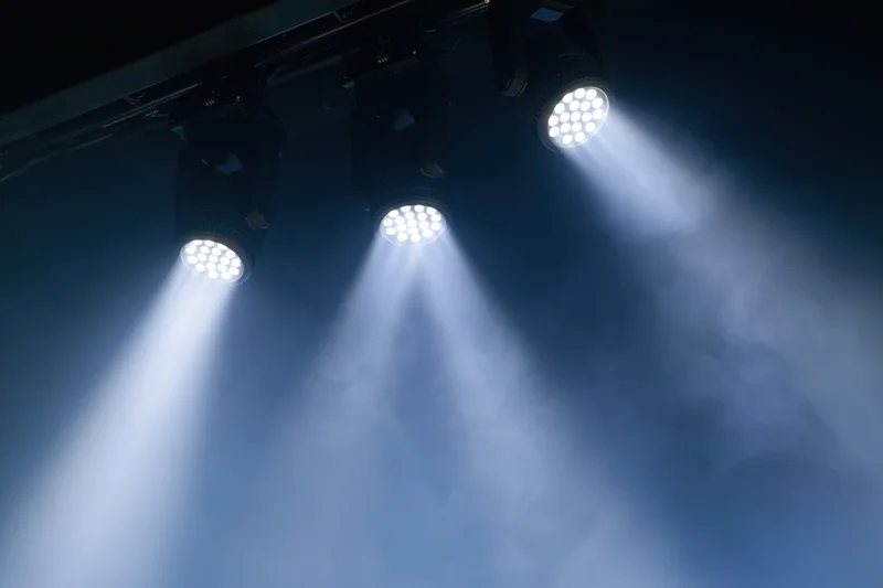Three led par lights mounted on ceiling rig casting beams through smoke in dark venue
