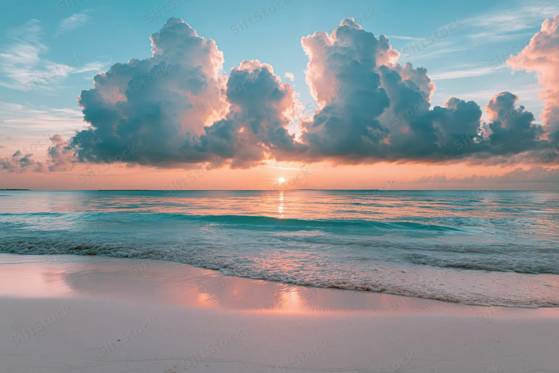 Tropical beach at sunset viewed from wet sand with waves rolling in and clouds above the horizon