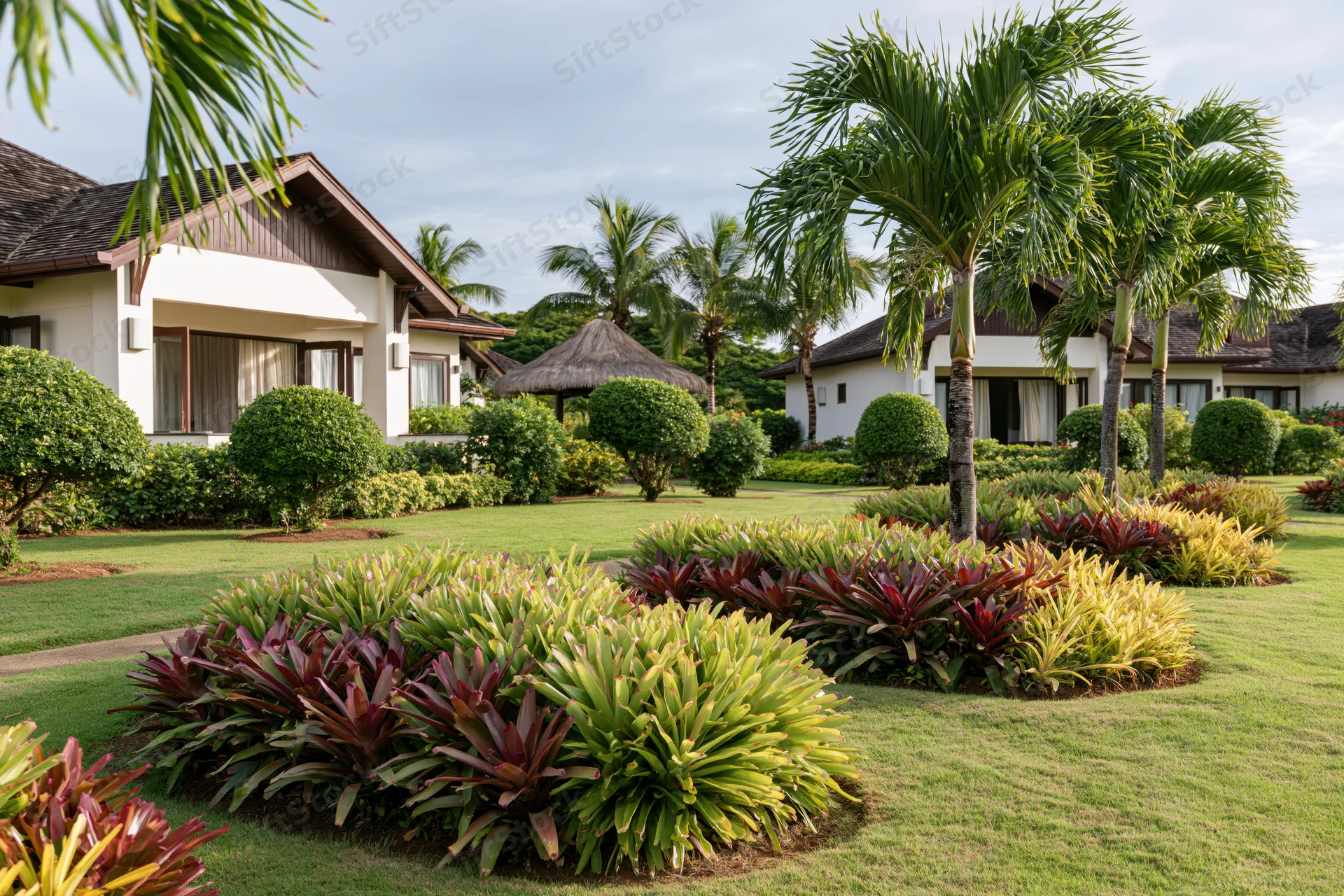 Tropical resort villa exterior with manicured garden and palm trees on a grassy lawn