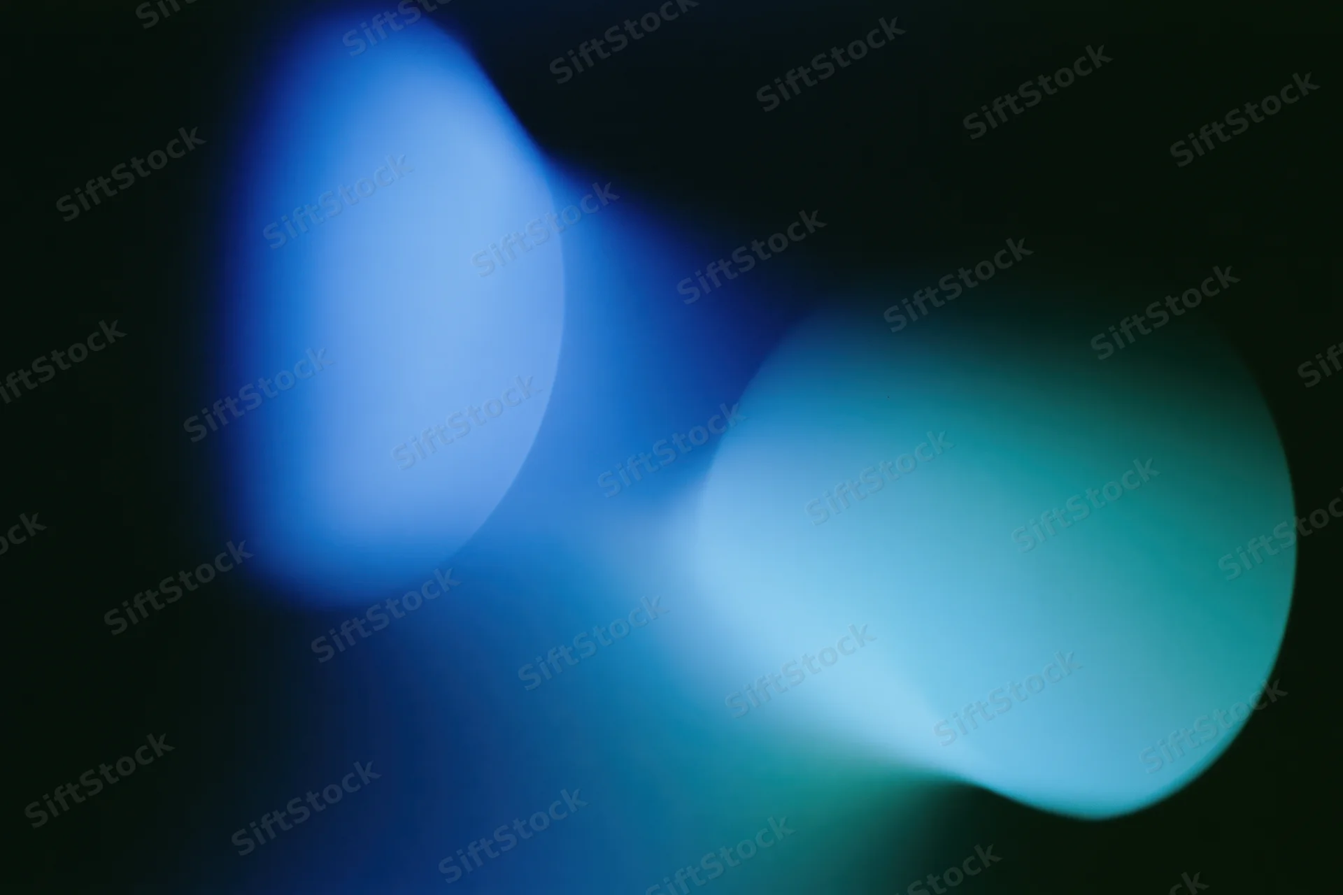 Two soft overlapping light leaks in deep electric blue and teal against dark background