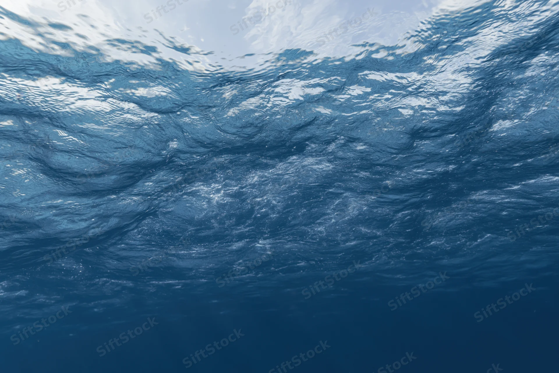 Underwater view looking up at rippling ocean surface with sunlight filtering through