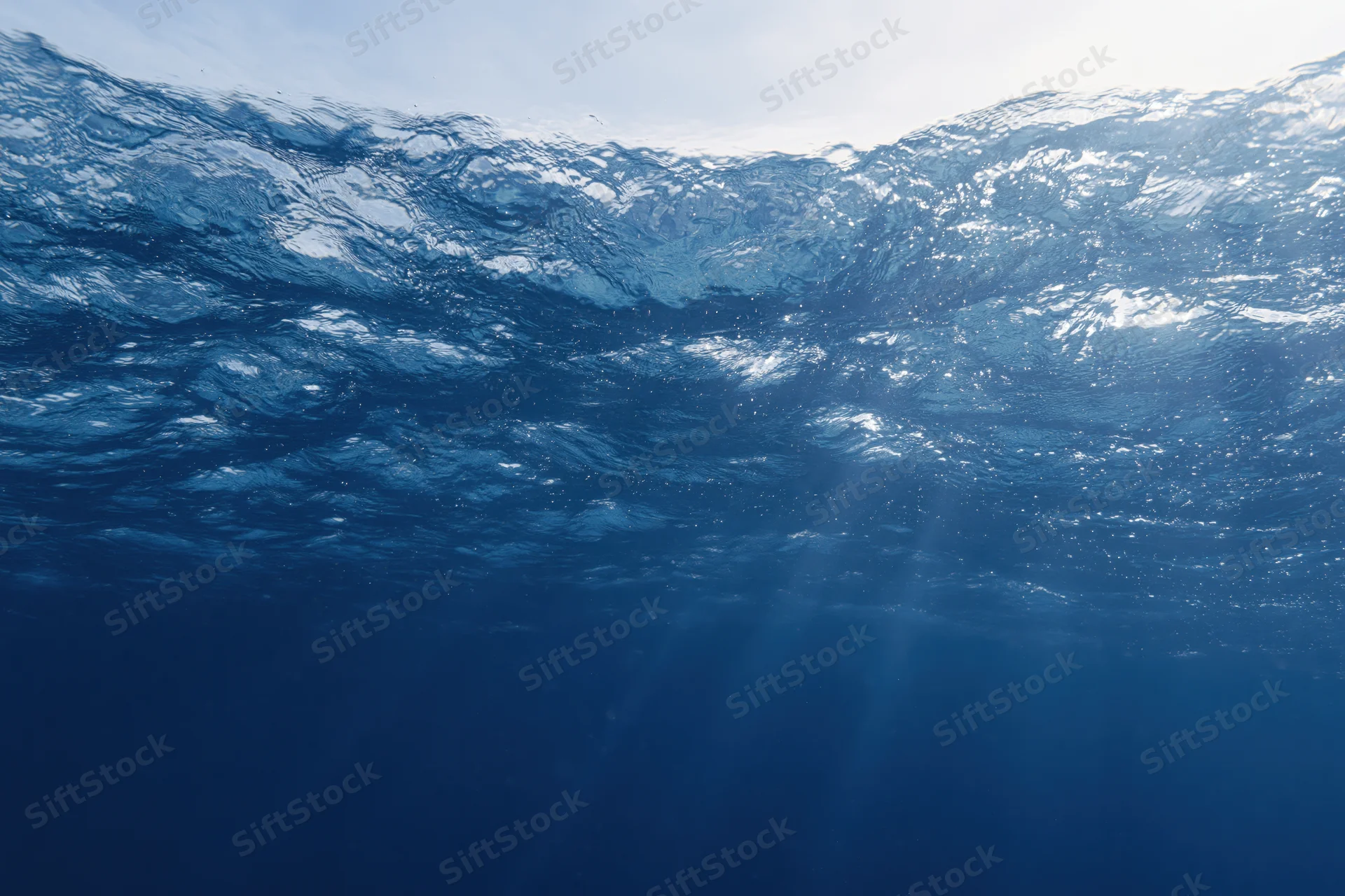 Underwater view looking up through rippling ocean surface toward sunlight