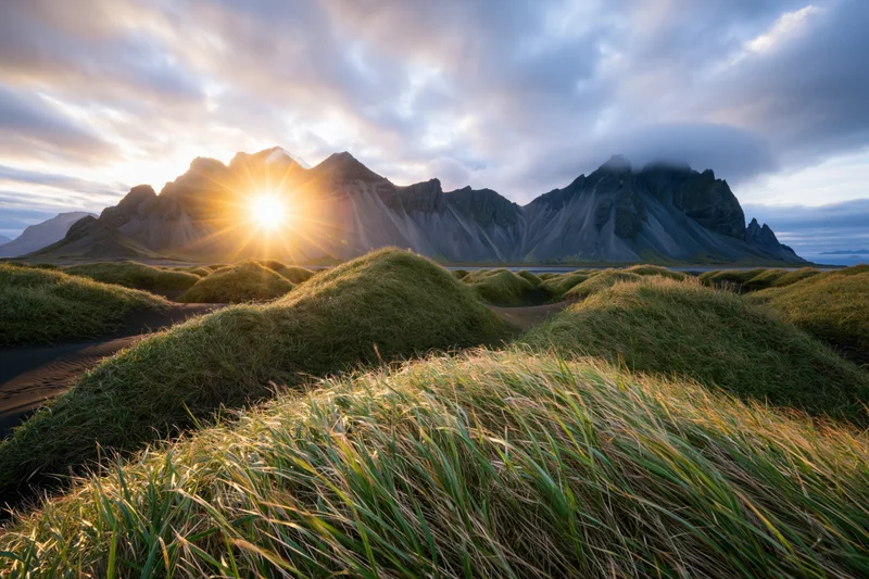 Grass-covered dunes in front of vestrahorn mountain range at sunrise