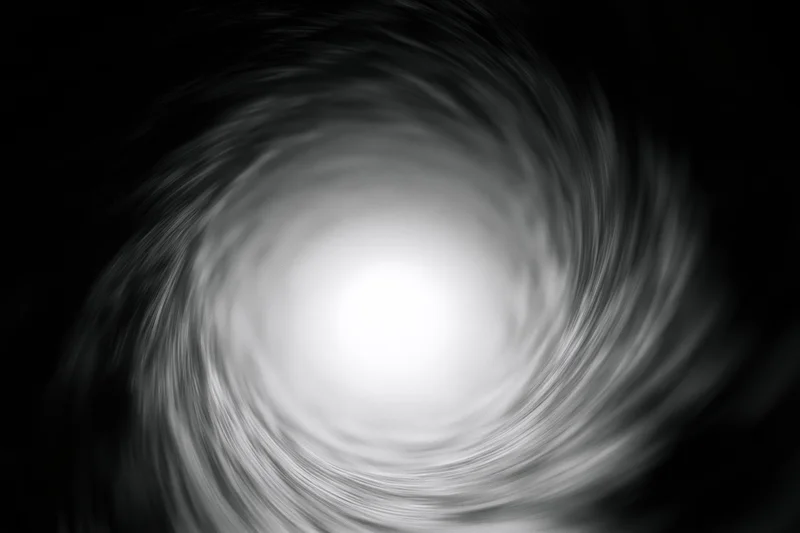 View from inside a dark circular tunnel looking toward a bright light at the center