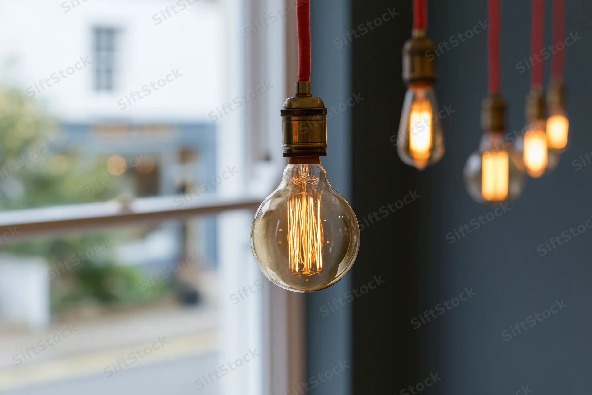 Vintage edison filament bulbs hanging from red cloth cables in interior space