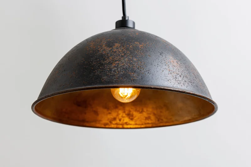 Vintage industrial dome pendant lamp hanging from ceiling with exposed Edison bulb emitting warm glow