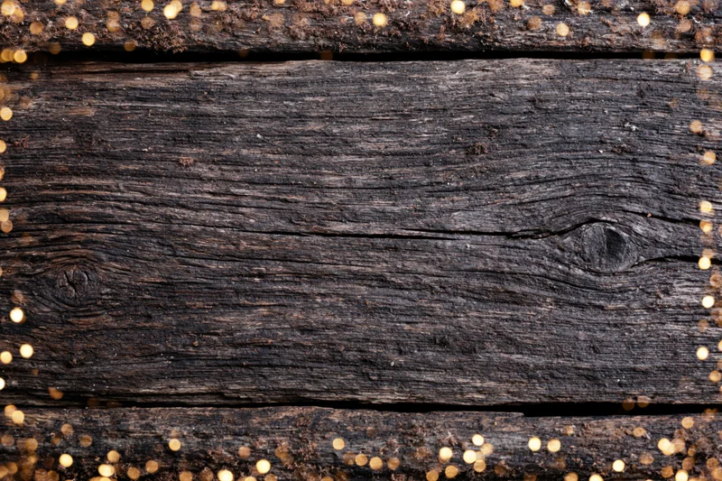 Dark weathered wooden planks arranged horizontally with gold glitter border and central copyspace