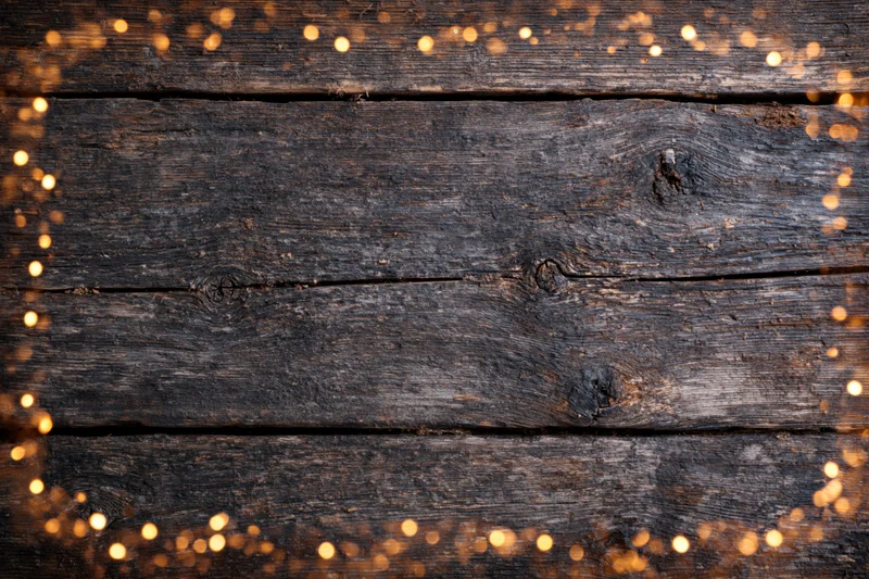 Dark weathered wooden planks arranged horizontally with warm bokeh lights framing the edges