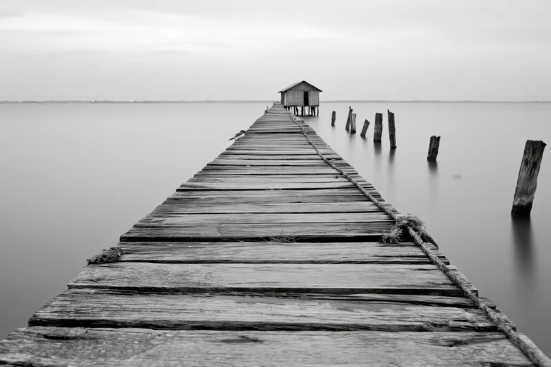 Weathered wooden fishing pier extending into calm estuary water