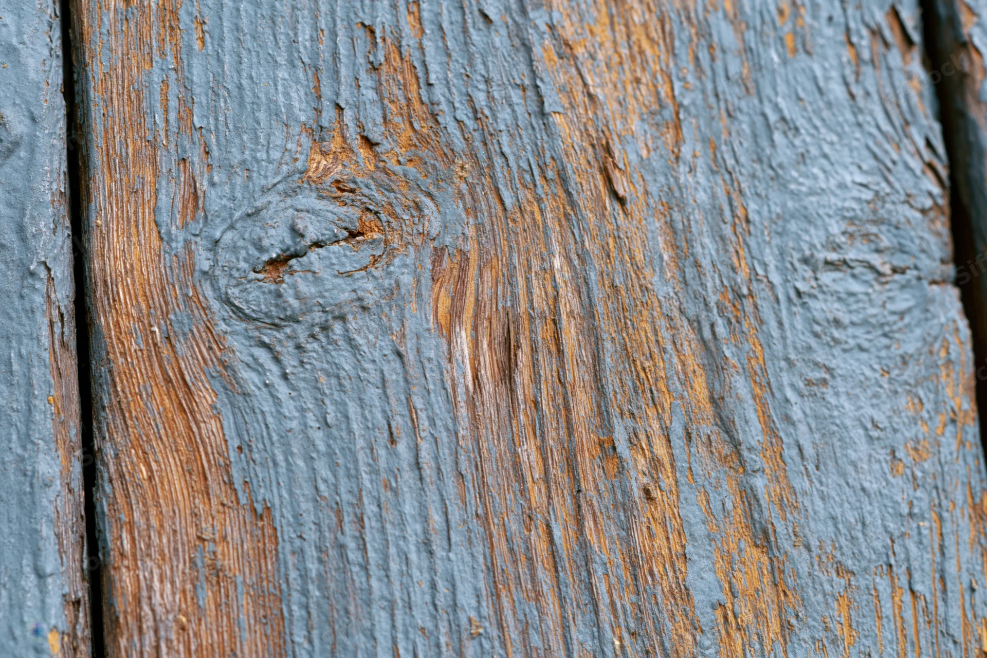 Weathered wooden plank surface filling the frame with peeling blue paint and visible grain
