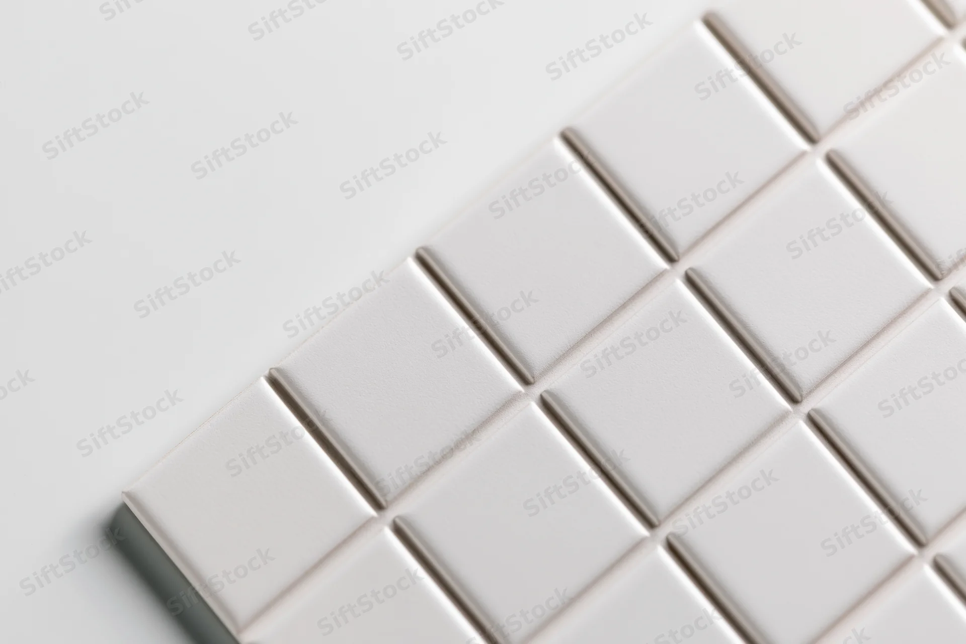White square ceramic tiles arranged diagonally in a grid pattern on a smooth surface