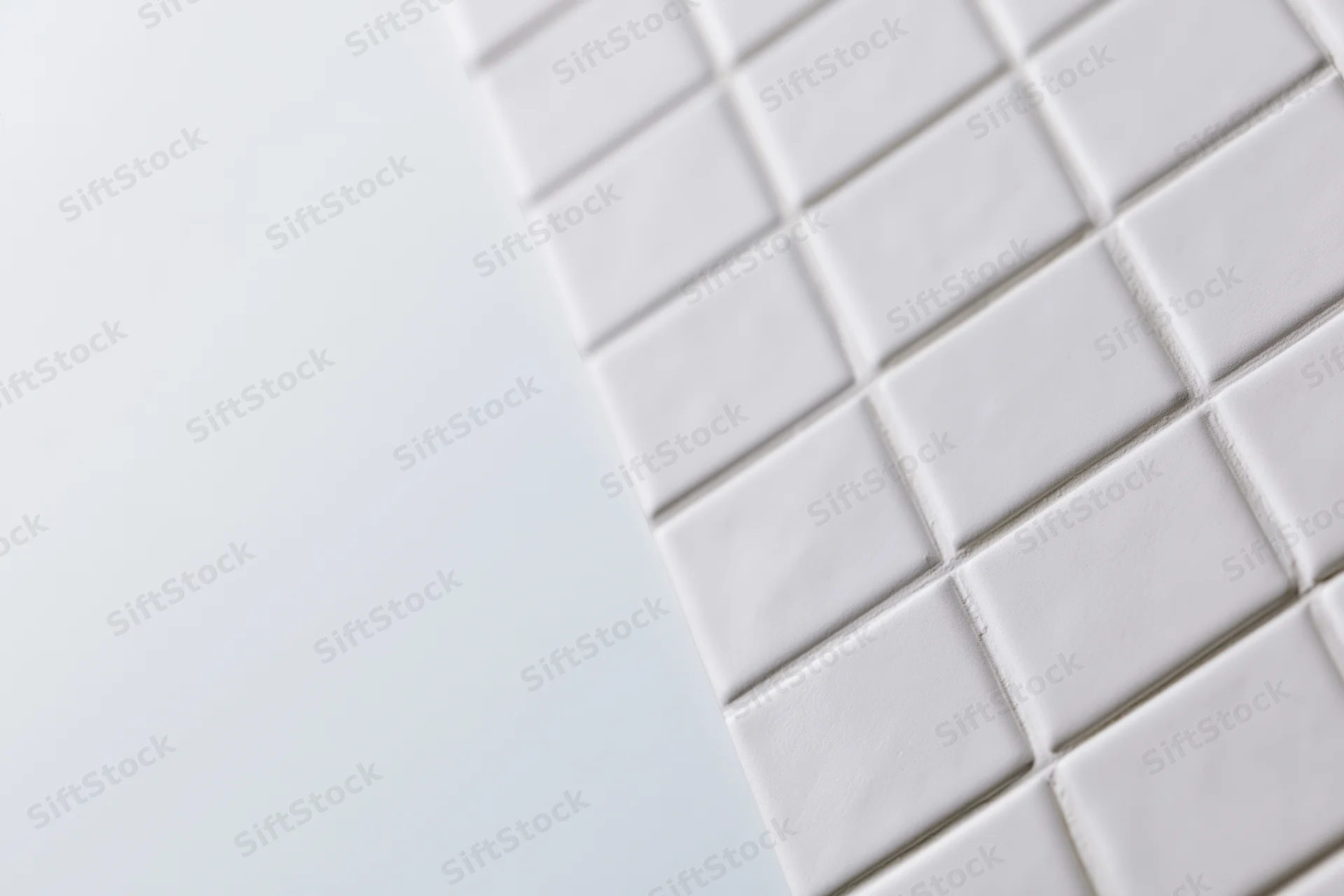 White square ceramic tiles arranged diagonally in a grid pattern on a wall surface