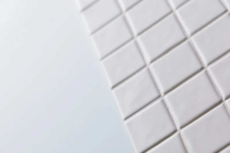 White square ceramic tiles arranged diagonally in a grid pattern on a wall surface