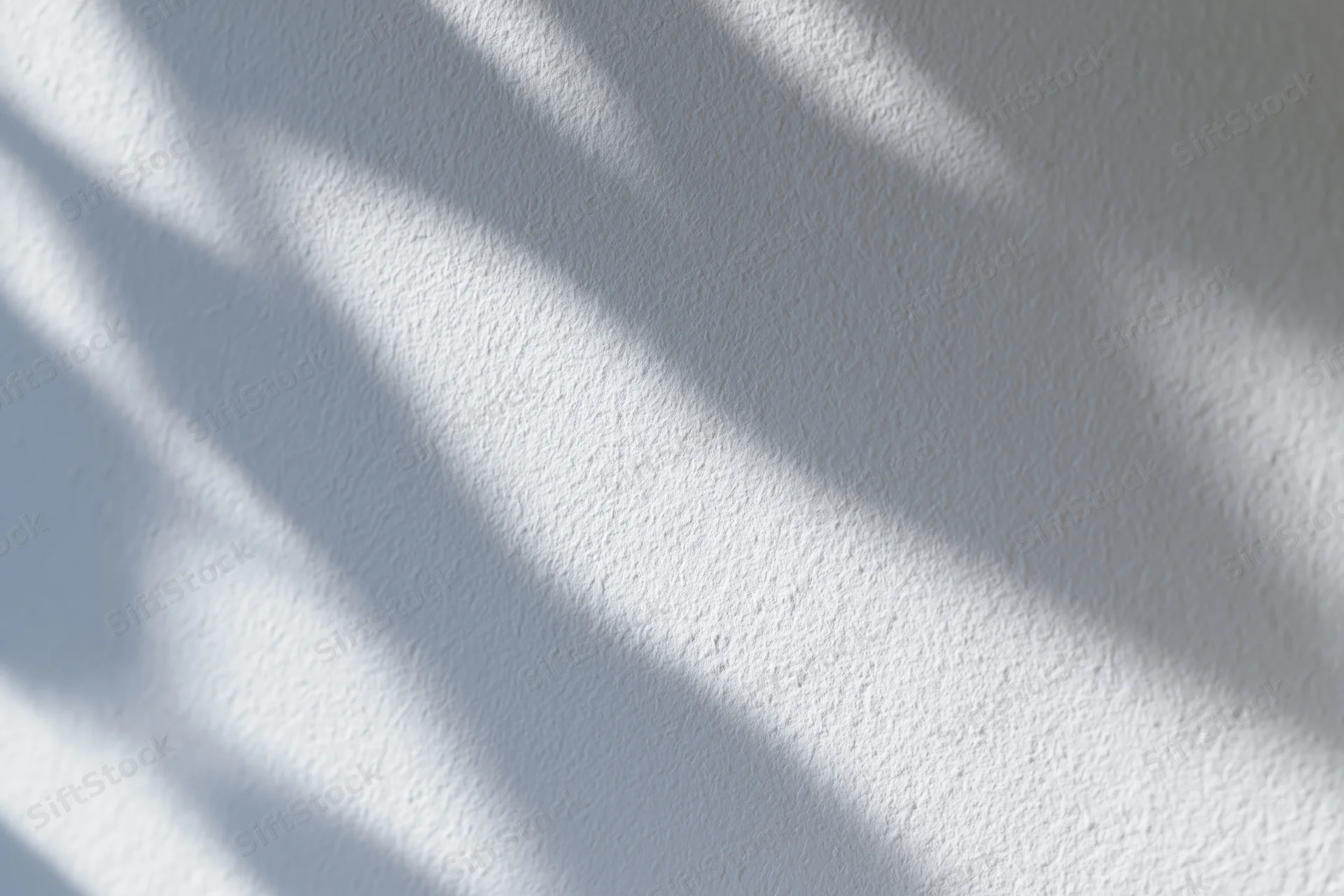 White textured wall with soft dappled leaf shadows from natural light