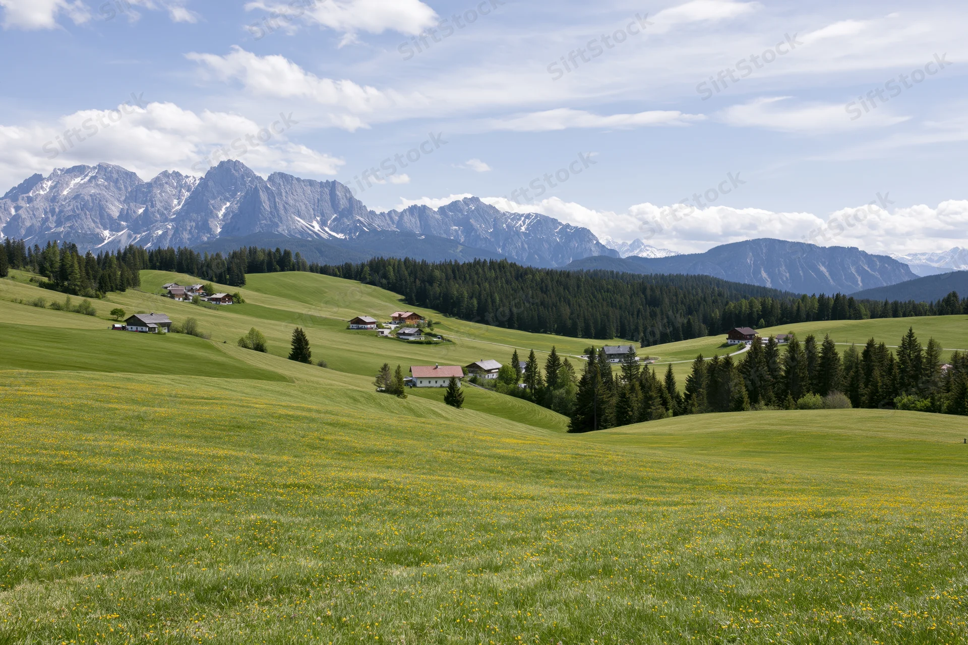 Rolling green meadows with scattered farmhouses and distant snow-capped mountains under a partly cloudy sky