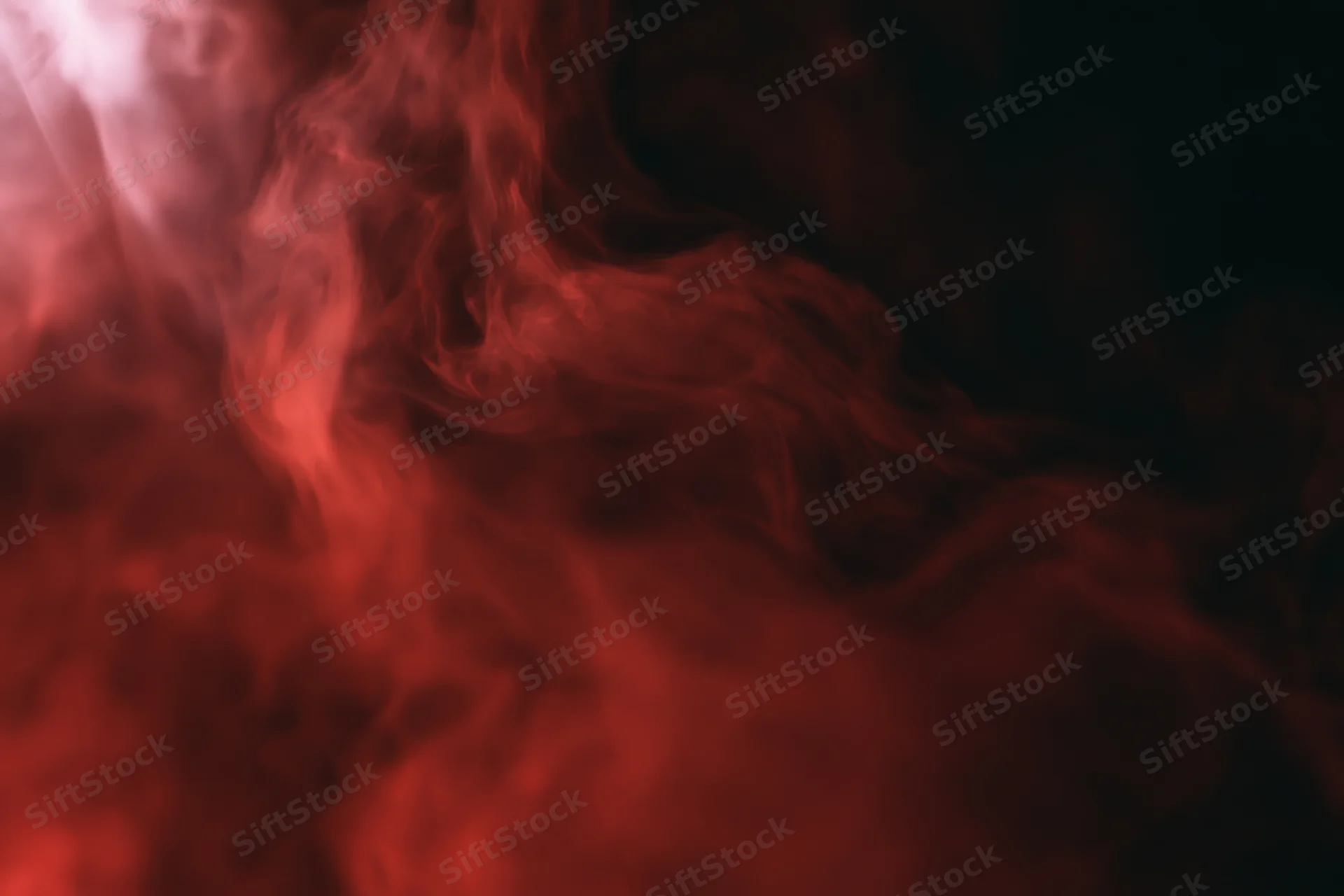 Red smoke swirling and drifting against a black background
