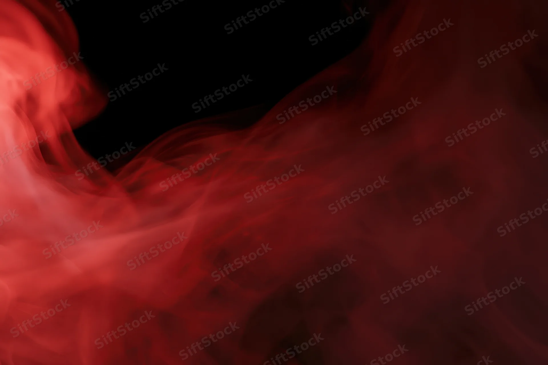 Red smoke swirling and drifting against a black background