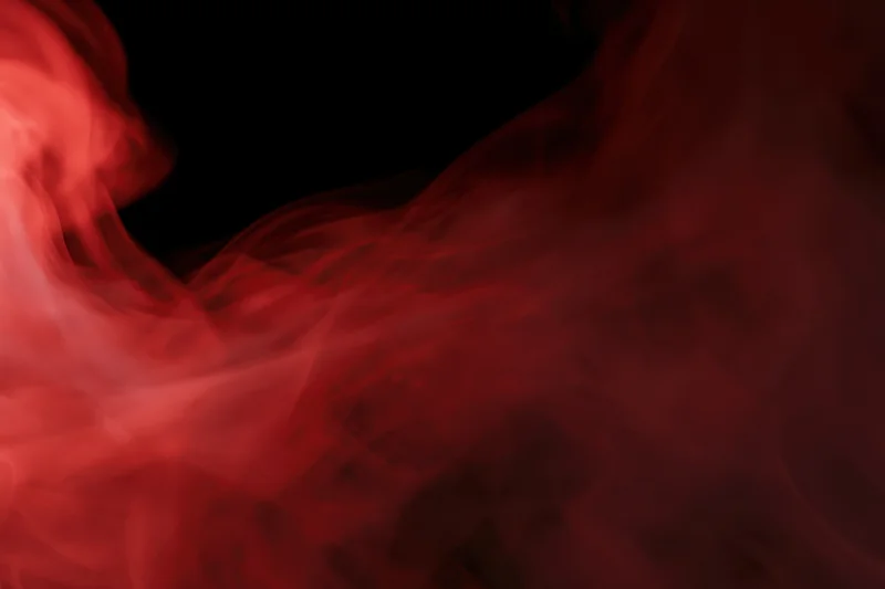 Red smoke swirling and drifting against a black background