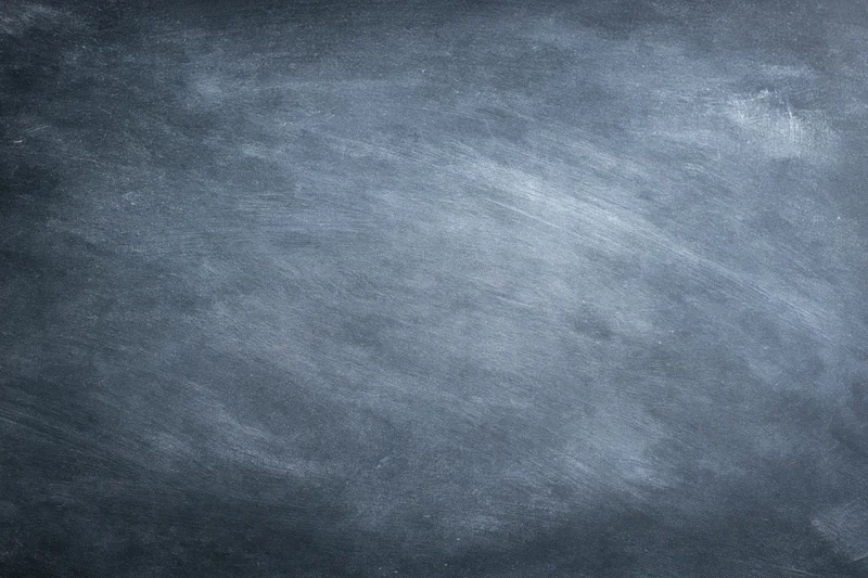 Worn chalkboard surface filling the frame with smudged chalk residue and textured grain