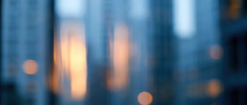 Blurred city skyline with glowing windows at dusk