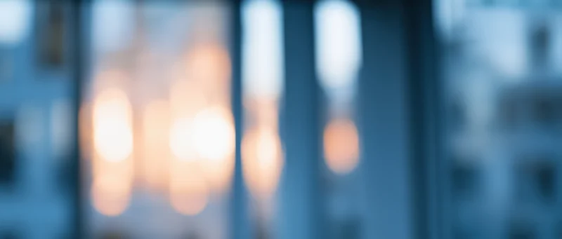 Blurred lights from a city window at twilight showing warm glow through glass