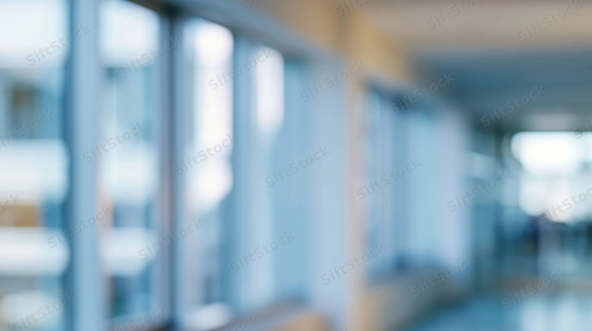 Blurred view of an office hallway with glass partitions and soft ambient light