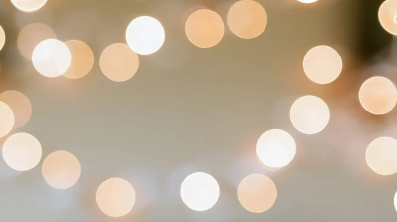 Blurred circular lights arranged in a frame around a soft neutral background with copyspace in center