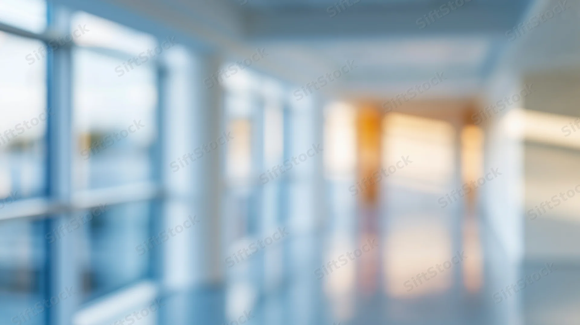 Blurred view of a modern office hallway with glass windows and bright lighting