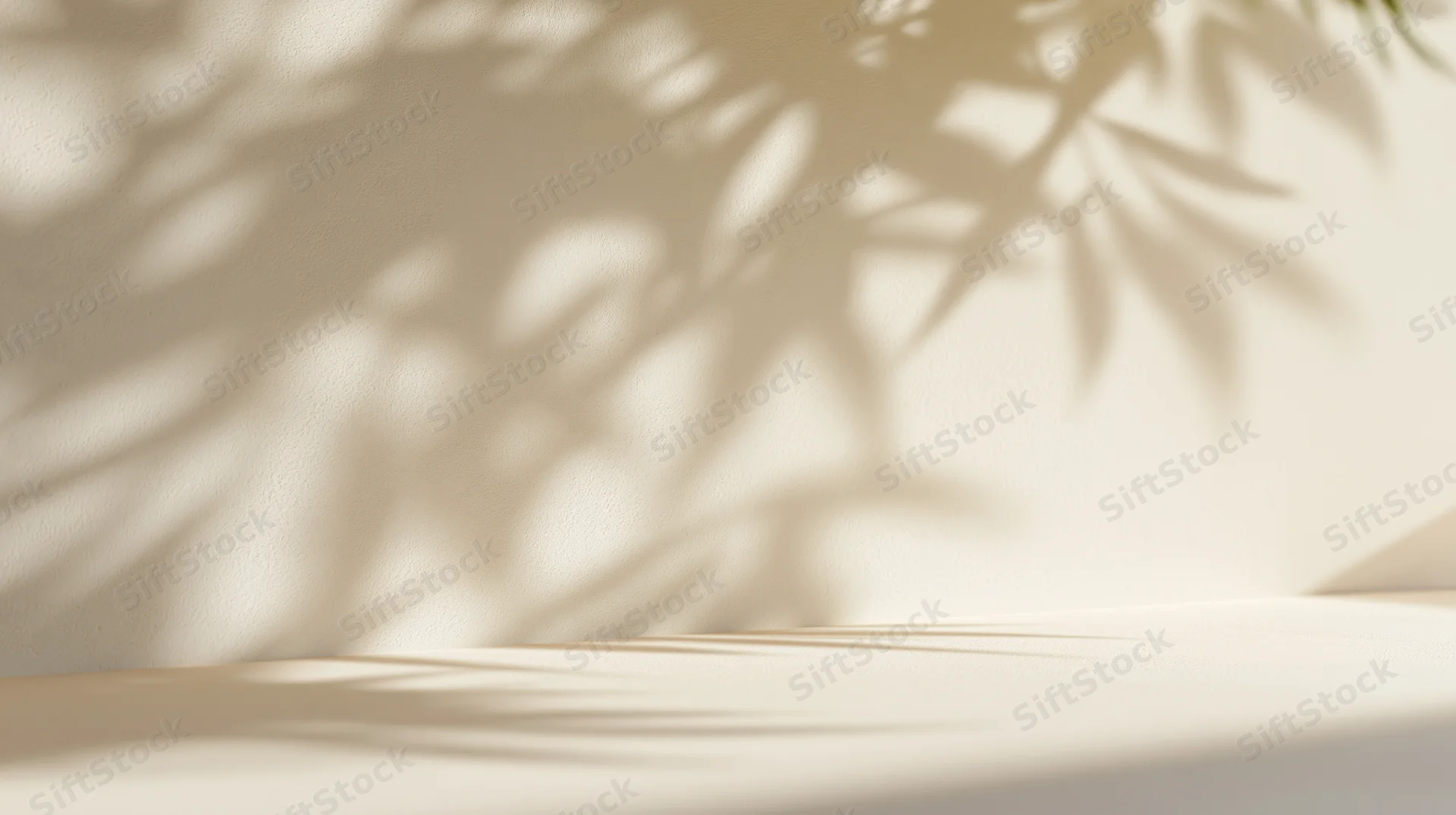 Dappled leaf shadows on a beige wall and surface in a minimalist interior