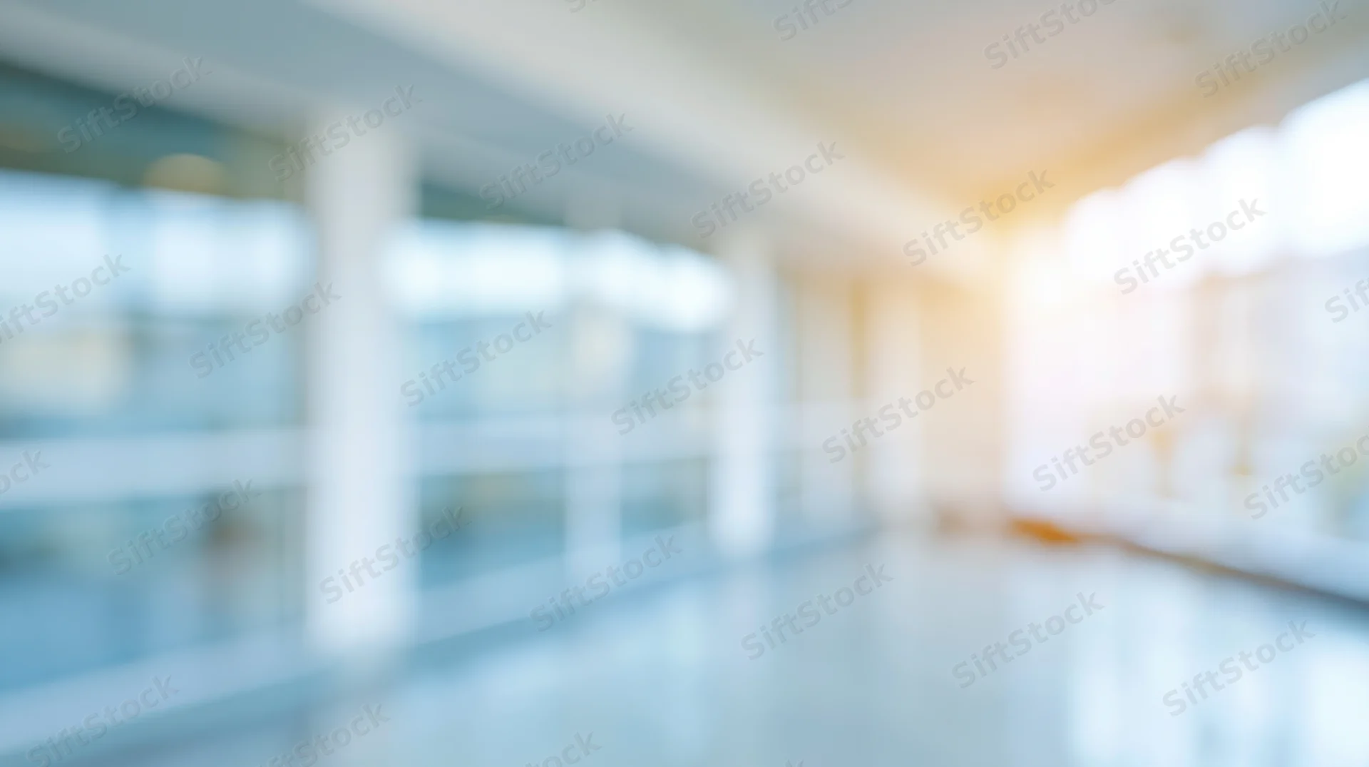 Blurred interior of a modern office hallway with glass walls and bright lighting