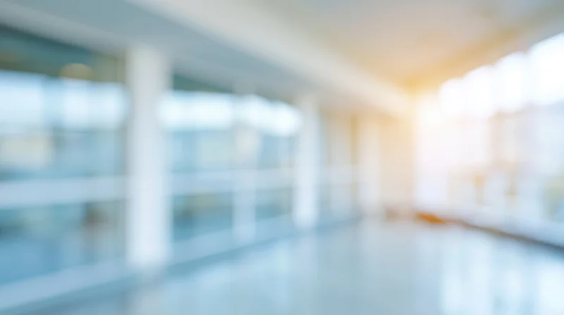 Blurred interior of a modern office hallway with glass walls and bright lighting