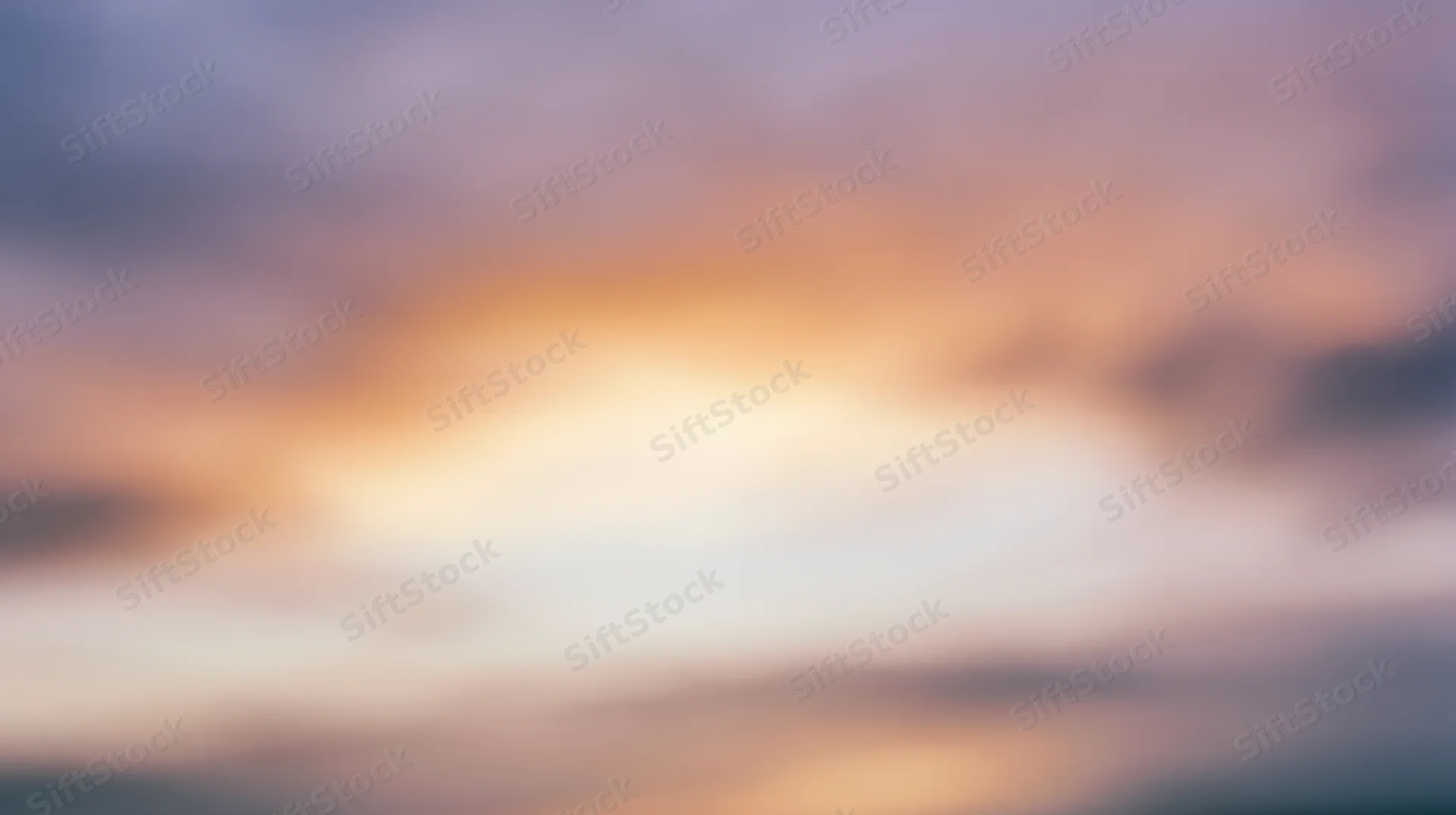 Blurred sky at sunset with soft orange and purple clouds filling the frame