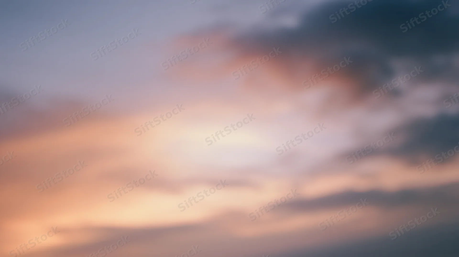 Soft blurred sky at twilight with orange and pink clouds against a blue gradient background