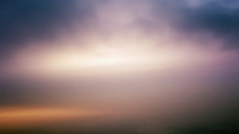 Soft pastel sky at twilight with layered clouds and gradient hues from horizon to upper atmosphere