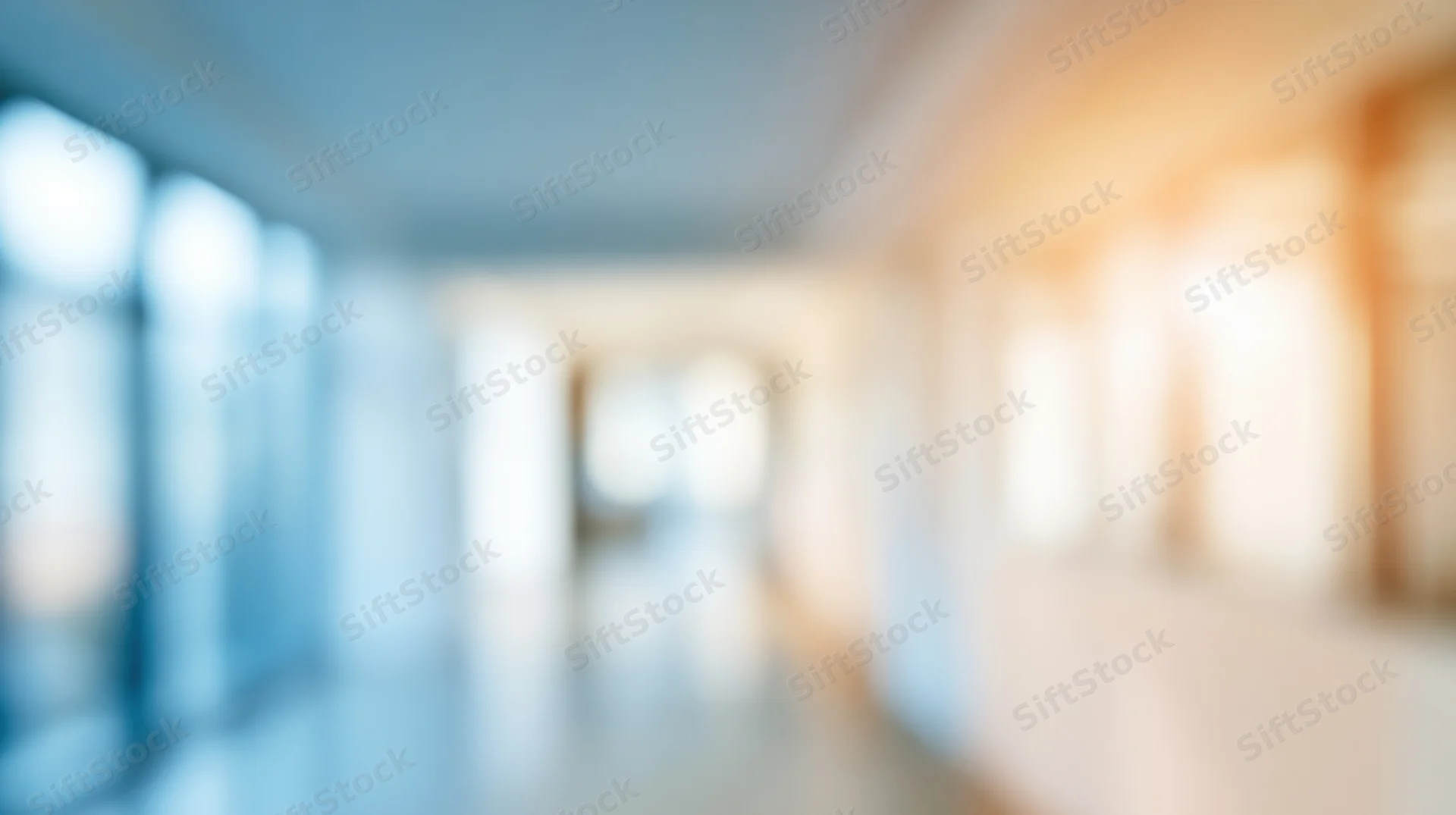 Blurred hallway in modern office interior with glass walls and warm ambient lighting