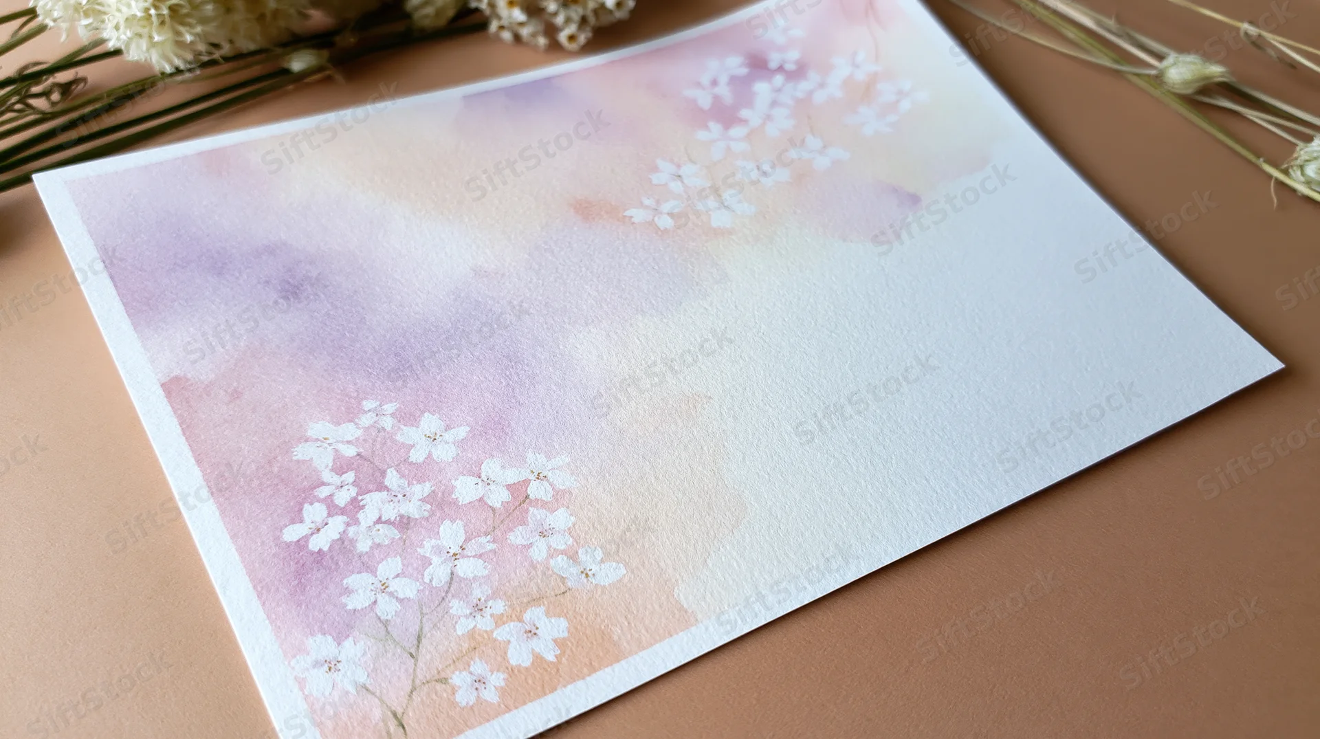 Watercolor floral card with pastel blossoms on textured paper, arranged flat on a warm surface with dried flowers nearby